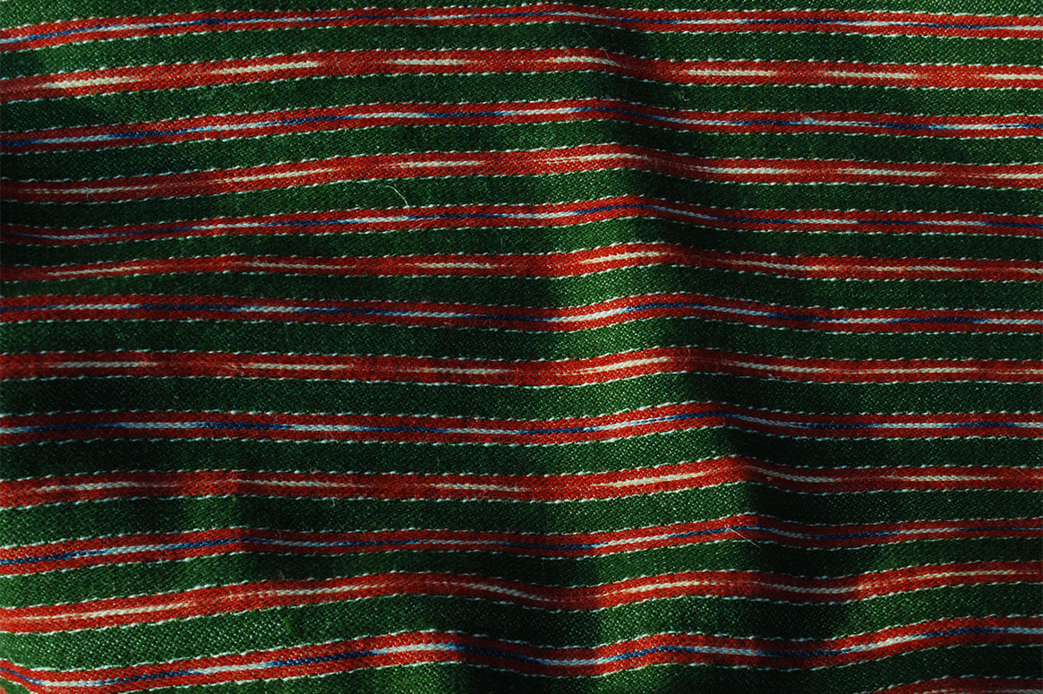 Randigt halvylle med grön basfärg och röda ränder. I de röda ränderna finns smala ränder av ikatfärgat garn i blått/vitt och rött/vitt.